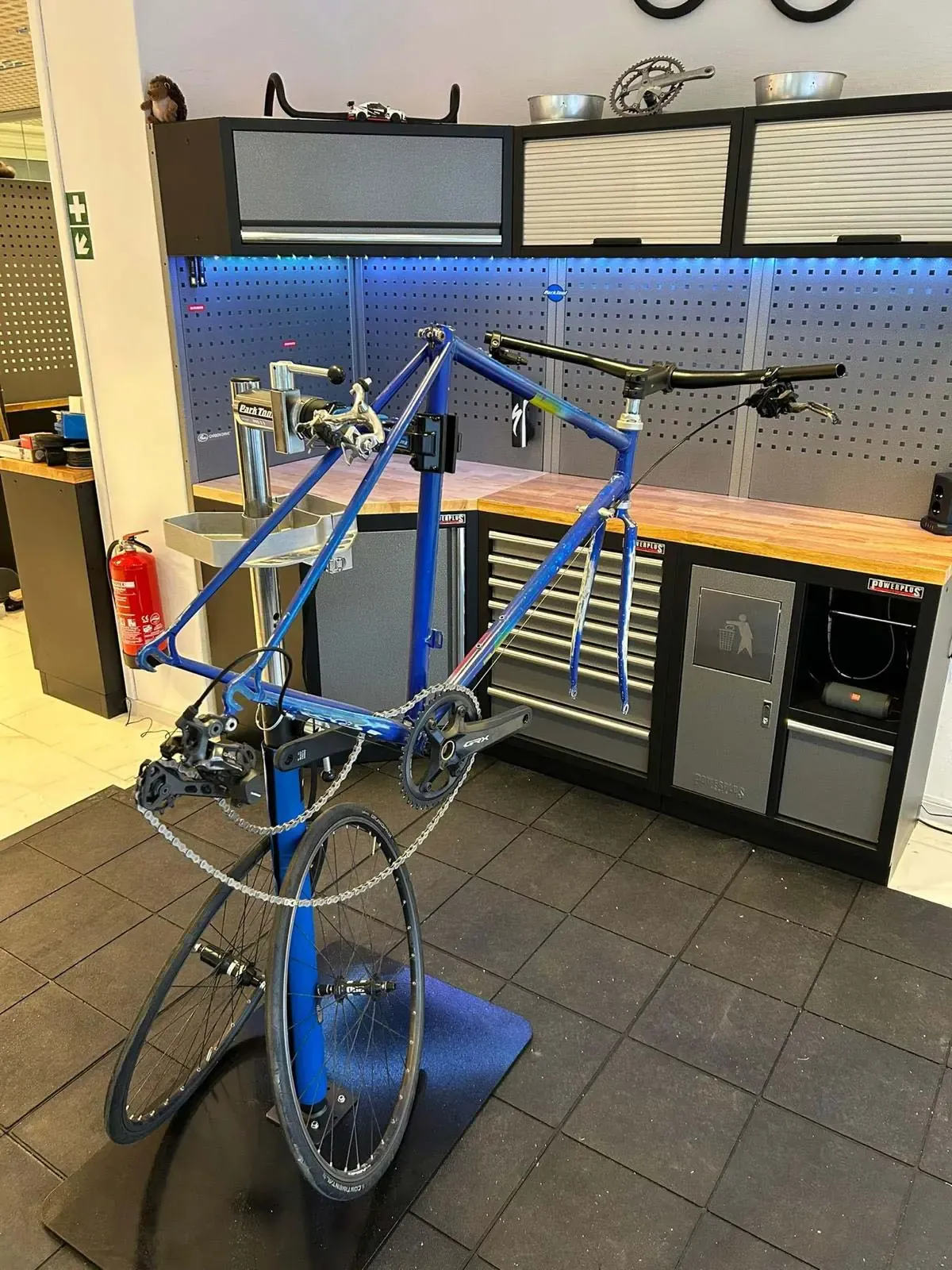 A bicycle frame without wheels is mounted on a repair stand in the workshop.