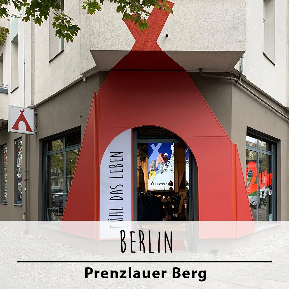 Die Ecke eines Gebäudes mit einem roten Tipi-förmigen Eingang und Schaufenstern.