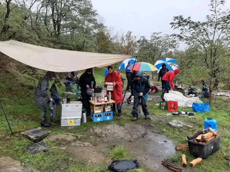 Eine Gruppe von Menschen unter einem Zelt im Freien, die sich um einen Tisch versammelt haben.